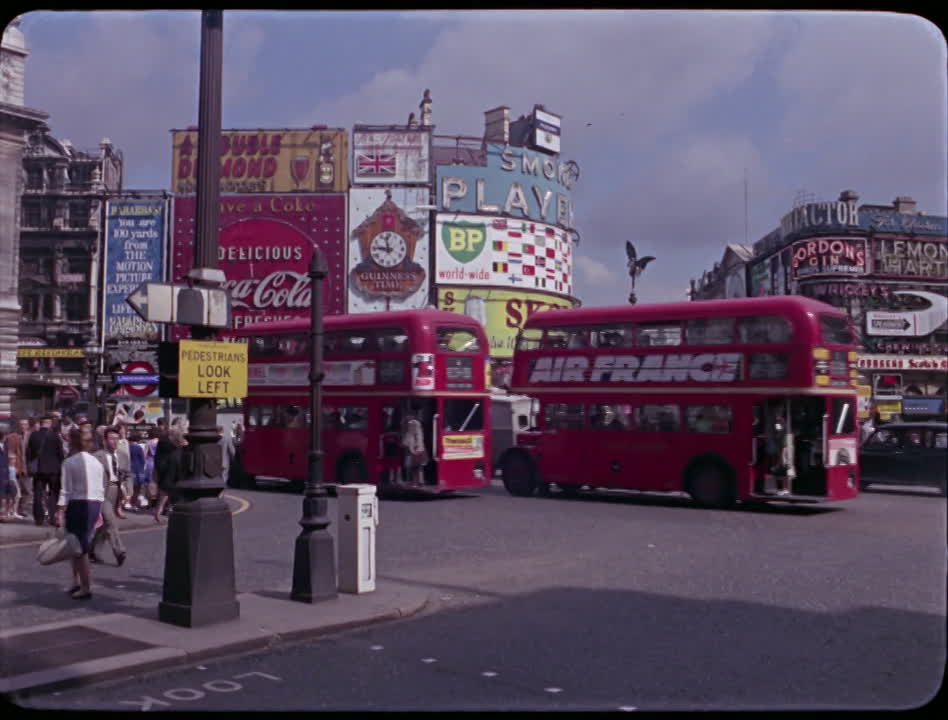 A 1960s London street scene with red double-decker buses